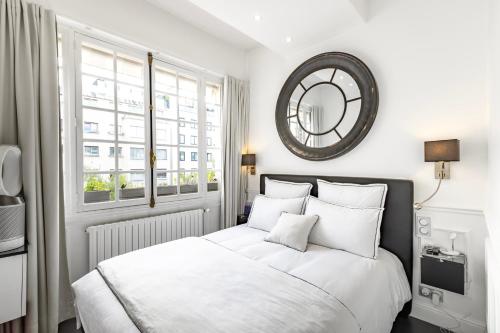 - une chambre avec un lit blanc et un miroir mural dans l'établissement Sublime appartement climatisé proche Paris et Boulogne, à Neuilly-sur-Seine