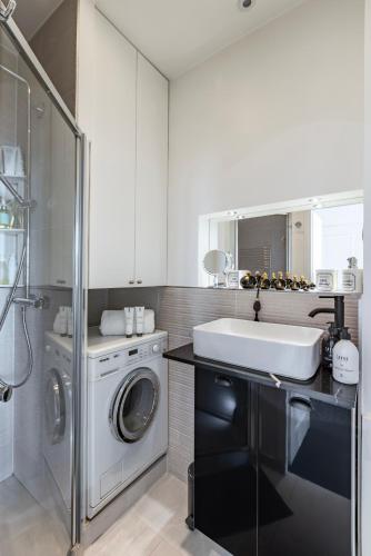 une salle de bain avec une machine à laver et un lavabo dans l'établissement Sublime appartement climatisé proche Paris et Boulogne, à Neuilly-sur-Seine
