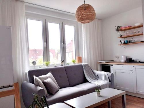 salon z kanapą i oknami w obiekcie Apartament Plaża Zachodnia - 400 m do morza w Kołobrzegu