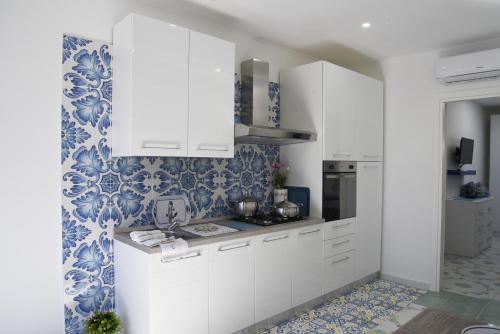 a kitchen with white cabinets and blue and white wallpaper at La Laura di Paestum - case vacanze in Capaccio-Paestum