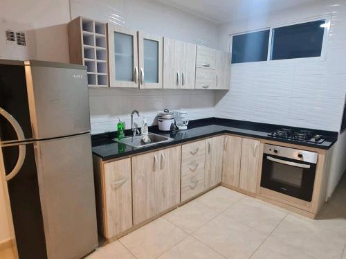 a kitchen with wooden cabinets and a stainless steel refrigerator at Apartamentos la flora in Cali