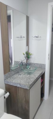 um balcão de casa de banho com um lavatório e um espelho em Apartamento Torres Center em Torres