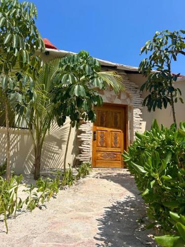 a house with a wooden door and a tree at Alquimia Hotel Boutique in Tulum
