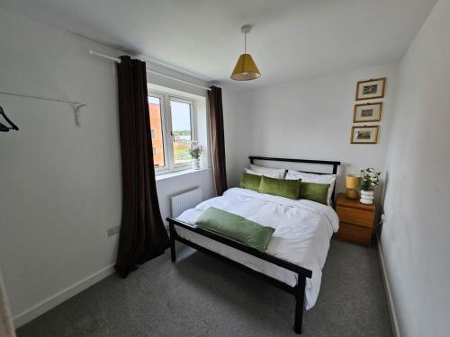 Un dormitorio con una cama con almohadas verdes y una ventana en Modern 3 Bedroom Town House in Ipswich en Ipswich