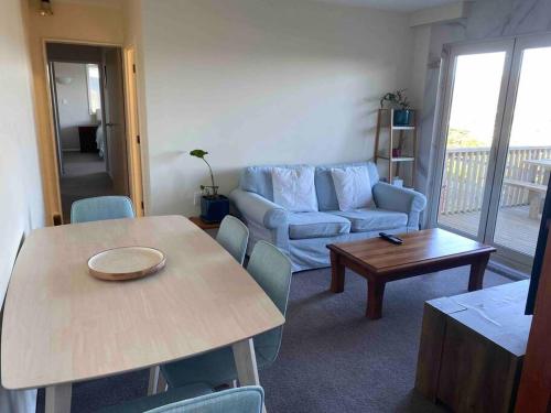 a living room with a table and a couch at 3 bed apartment with stunning harbour views in Lower Hutt