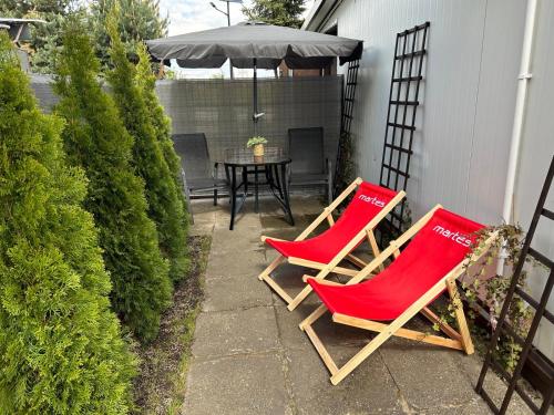 2 sillas rojas y una mesa con sombrilla en Marlina, en Niewiesze