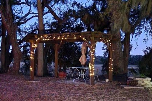 a wooden pergola with a table and lights at A Secluded Quiet Oasis with Beach Pass in St. Helena Island