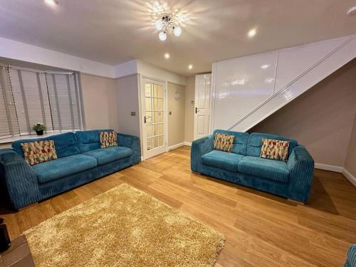 a living room with two blue couches and a staircase at Accessible home in Sherwood in Nottingham