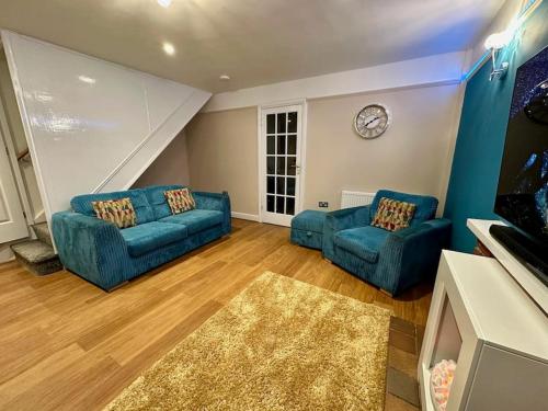 a living room with two blue couches and a clock at Accessible home in Sherwood in Nottingham