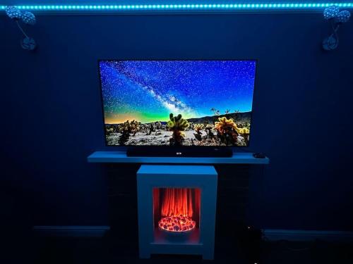 a tv sitting on a blue wall with a fireplace at Accessible home in Sherwood in Nottingham
