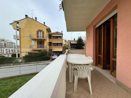 une table et des chaises blanches assises sur un balcon dans l'établissement Igea vacanza, à Bellaria-Igea Marina
