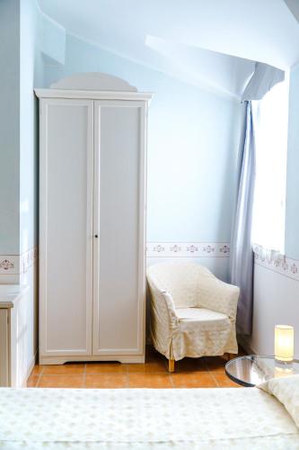 a bedroom with a white cabinet and a chair at Caroline Hotel in Brusimpiano