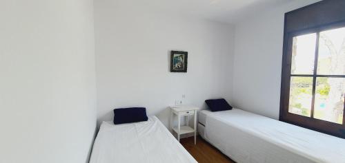 2 Betten in einem Zimmer mit Fenster in der Unterkunft COSTA BRAVA SUITES VILLA Cala Jonca in Sant Feliu de Guixols