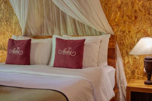 een slaapkamer met een bed met paarse kussens en een baldakijn bij Asoka Bungalows in Nusa Penida