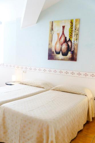 two beds in a room with a painting on the wall at Caroline Hotel in Brusimpiano
