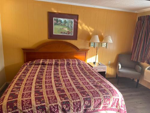 Habitación de hotel con cama y silla en Economy Inn - Cullman, en Cullman