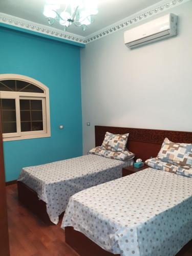 a blue room with two beds and a window at Magic Vella in Al Aqālitah
