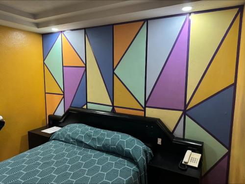 ein Schlafzimmer mit einer farbenfrohen Wand und einem Bett in der Unterkunft Hotel Gama in Mexiko-Stadt
