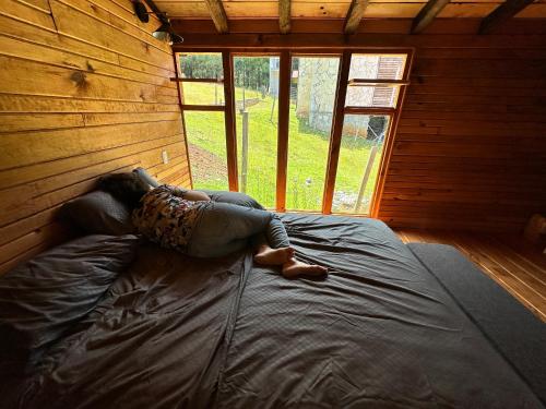 a woman laying on a bed in a cabin at Cabaña Magnolia in Nuevo León