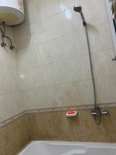 een douche in een badkamer met een wit bad bij Rest house in Seeb