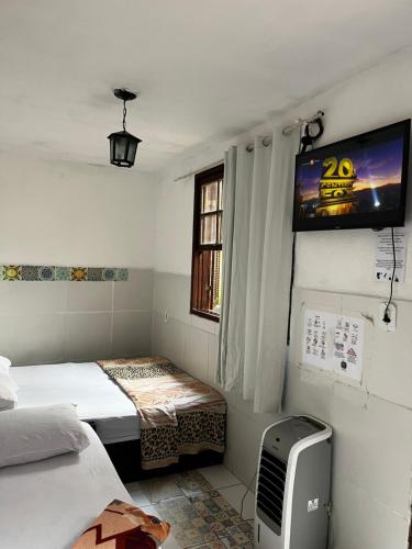 a small room with two beds and a tv at Hostel Uai in Ouro Preto