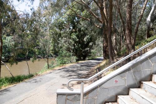 a road with stairs next to a river with trees at Corporate Living Accommodation Abbotsford in Melbourne