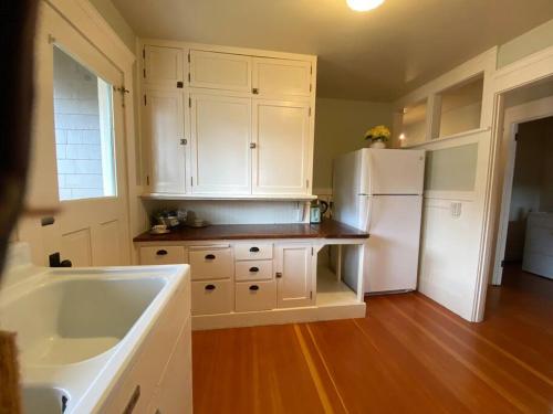 uma cozinha com armários brancos e um frigorífico branco em Historic Downtown Riverview Flat, No. 4 em Astoria
