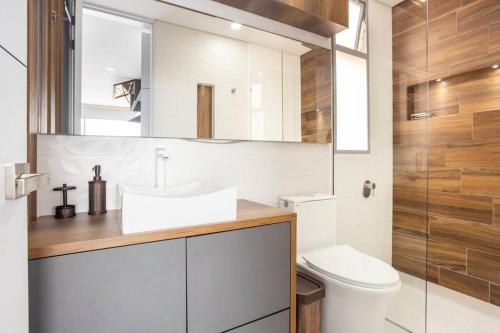 uma casa de banho com um WC, um lavatório e um espelho. em Medellin Luxury PH 22-Floor Incredible City View em Envigado