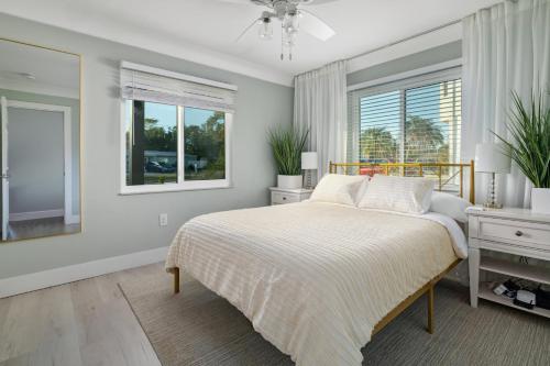 a white bedroom with a bed and two windows at NEW Dog Paradise - Near the Beach IMG & Downtown in Bradenton