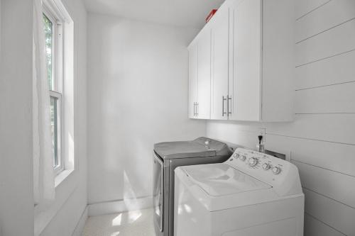 eine weiße Waschküche mit einer Waschmaschine und einem Fenster in der Unterkunft House on Cora - Sleeps 10 Hot Tub & Walk to Main in Fredericksburg
