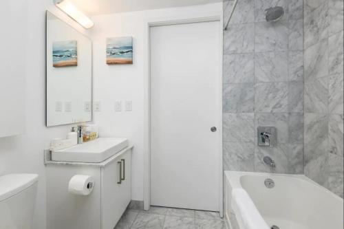 uma casa de banho branca com uma banheira e um lavatório em Executive 1 BR Condo - CN Tower & City View em Toronto
