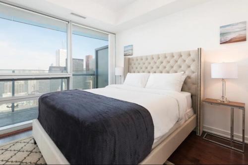 um quarto com uma cama grande e uma janela grande em Executive 1 BR Condo - CN Tower & City View em Toronto