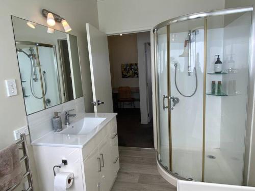 a bathroom with a glass shower and a sink at Rata Karaka Bach in Ngunguru