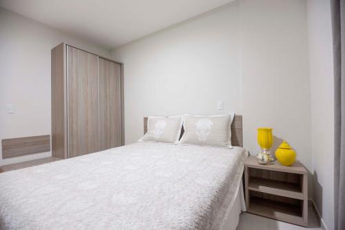 a white bedroom with a large bed with white sheets at Atrium Thermas Flat Service - OFICIAL in Caldas Novas
