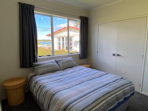 a bedroom with a large bed and a window at Rata Karaka Bach in Ngunguru