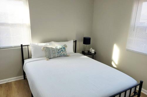 a white bed in a bedroom with two windows at Davenport Dwellings-Two Bedroom in Omaha