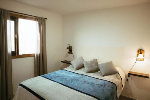 1 dormitorio con 1 cama con 2 almohadas y ventana en Cabañas Mailen'S en Puerto San Julian