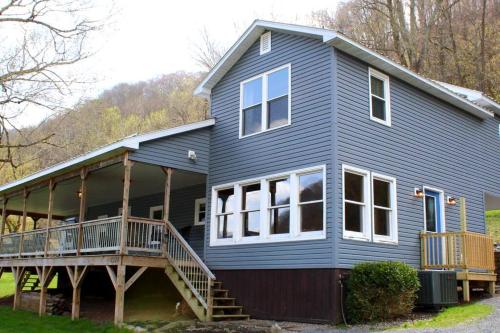 a blue house with a porch and a deck at Riverfront Property in NRG National Park near Sandstone Falls- Wi-Fi, Pet-Friendly in Hinton