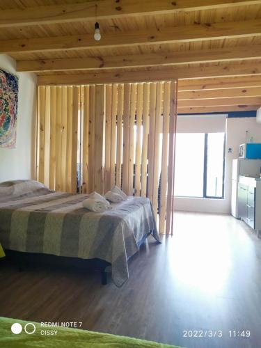 1 dormitorio con 1 cama y pared de madera en Departamento con Balcón en General Pico