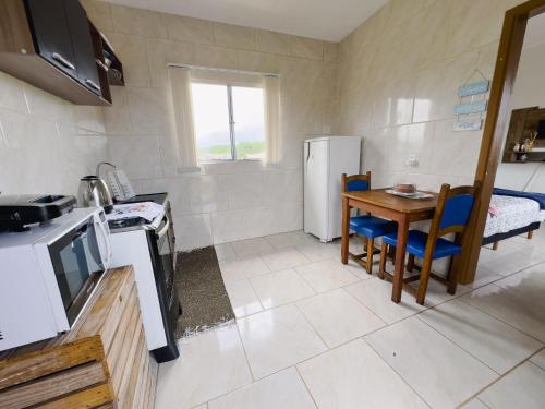 uma pequena cozinha com uma mesa e um frigorífico em Bella Praia apartamento Tartaruga em Passo de Torres