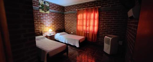 Zimmer mit 2 Betten und Ziegelwand in der Unterkunft El Belichito in Belén