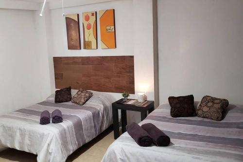 1 dormitorio con 2 camas y mesa con almohadas moradas en Departamento Comodo centrico Tv Ac wifi cocina parking, letra C en Ciudad Valles