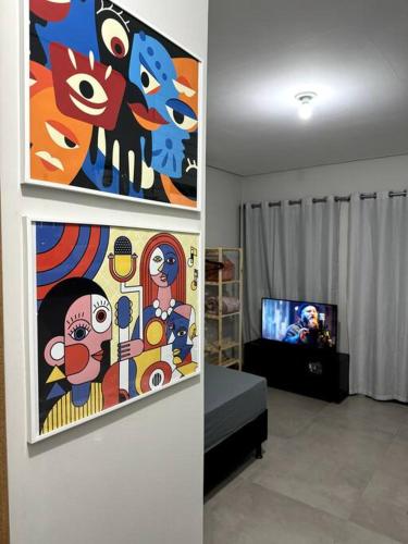 een woonkamer met een schilderij aan de muur en een tv bij 2- Studio Prox Uel e catuai c/ar in Londrina