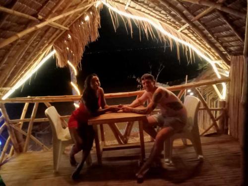 two people sitting at a picnic table in a hut at 8 Star Paradise in Locaroc