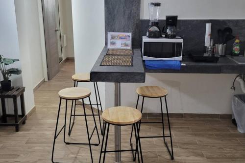 a counter with three stools in a kitchen at Departamento de 2 recamaras con 2 aires acondiconados, parking, wifi 70mb, refrigerador, micro,fregadero,licuadora,parrilla, cocina, D5 in Ciudad Valles