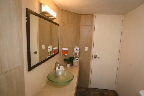 La salle de bains est pourvue d'un lavabo en verre et d'un miroir. dans l'établissement Departamento de 2 recamaras con 2 aires acondiconados, parking, wifi 70mb, refrigerador, micro,fregadero,licuadora,parrilla, cocina, D5, à Ciudad Valles
