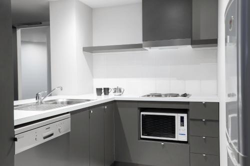 a white kitchen with a sink and a microwave at Mantra Southbank in Melbourne
