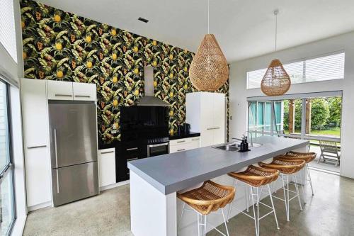 a kitchen with a large island with bar stools at The Mangawhai Bach in Mangawhai