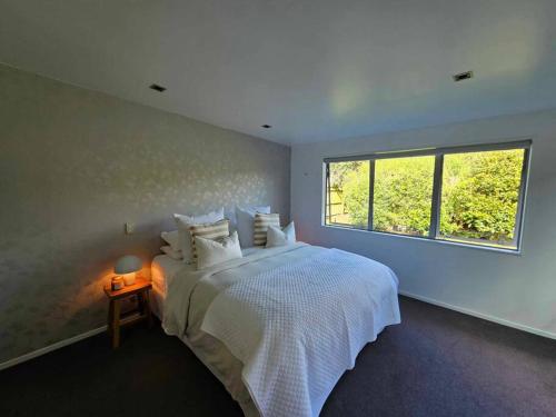 a bedroom with a white bed and a window at The Mangawhai Bach in Mangawhai