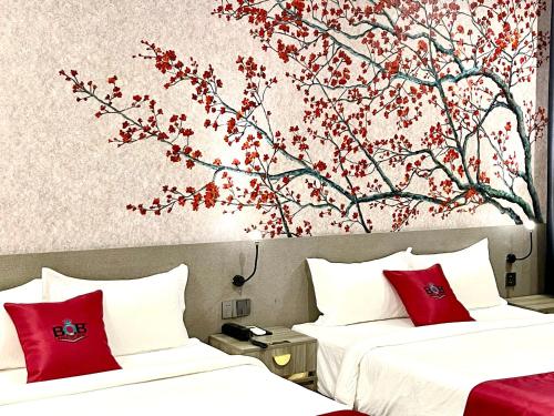 two beds in a hotel room with a tree mural at B.O.B Hotel in Cao Lãnh